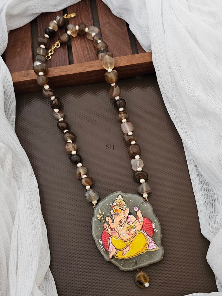 The Ganesh pendant, revered in Hinduism, adorns this necklace alongside brown and white beads. Symbolizing wisdom and remover of obstacles, Ganesh brings blessings. Crafted with care, this pendant necklace exudes spiritual significance and aesthetic charm. Wear it with reverence or as a fashion statement, carrying the essence of divine protection.